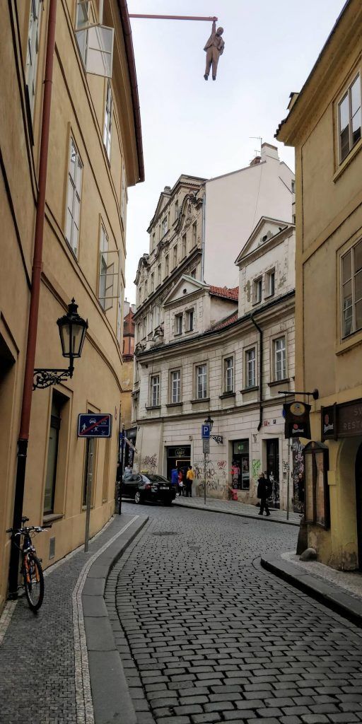 A man appears to be hanging over a street in an artistic installation, based in a city center, capturing a surreal, thought-provoking scene.
