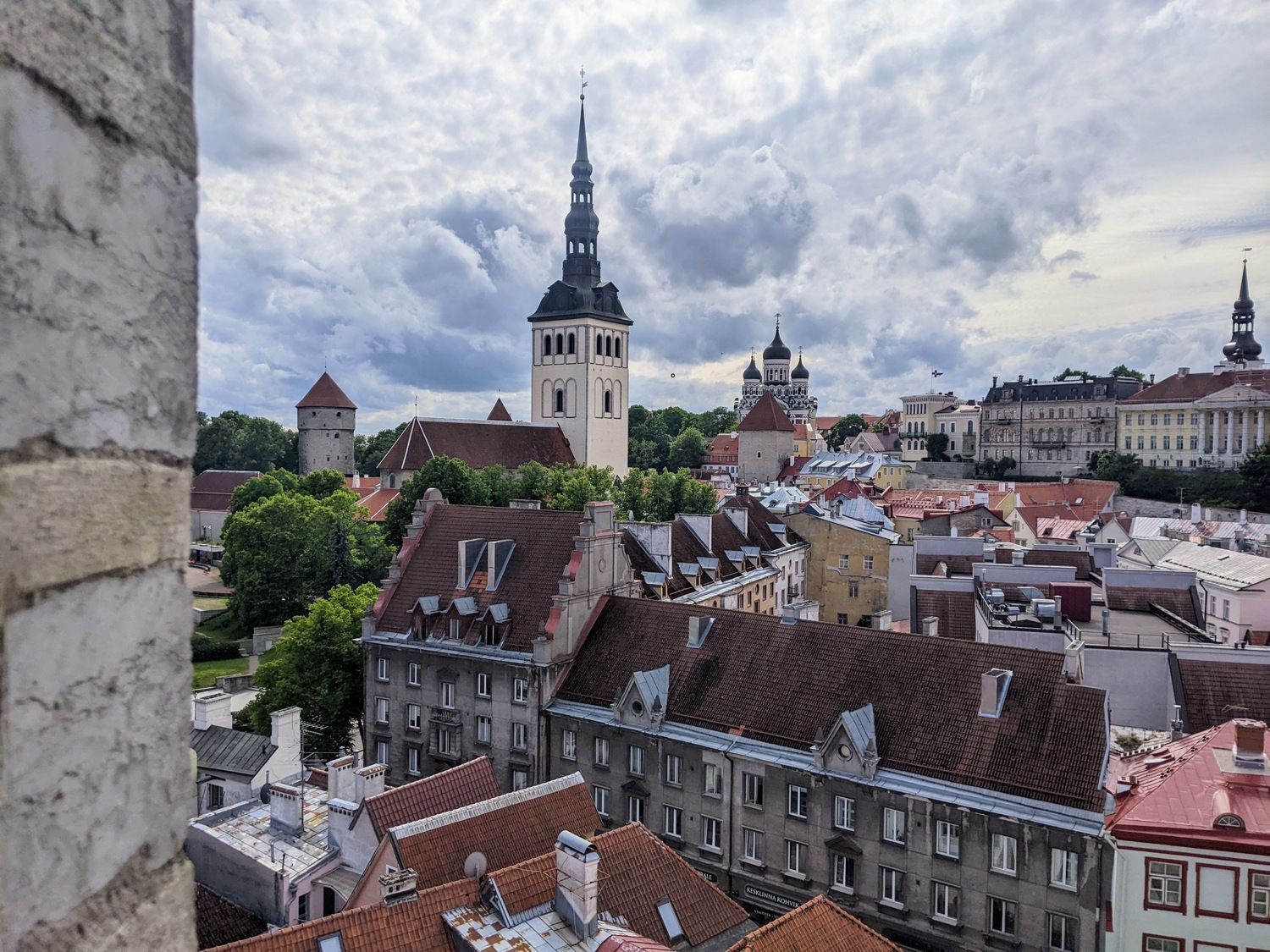 A cityscape of Tallinn's Old Town featuring historic buildings and red-roofed architecture under a clear sky.
