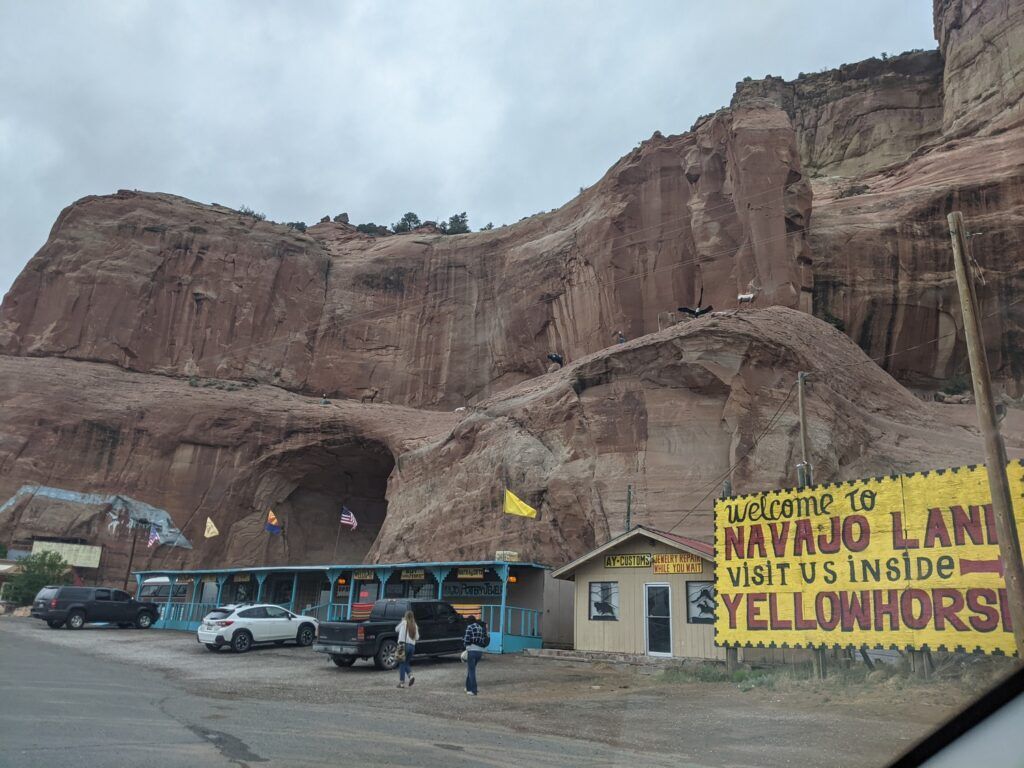 A trading post named Yellowhorse is depicted, showcasing a rustic building exterior in a desert environment with sparse vegetation and rugged terrain in the background.