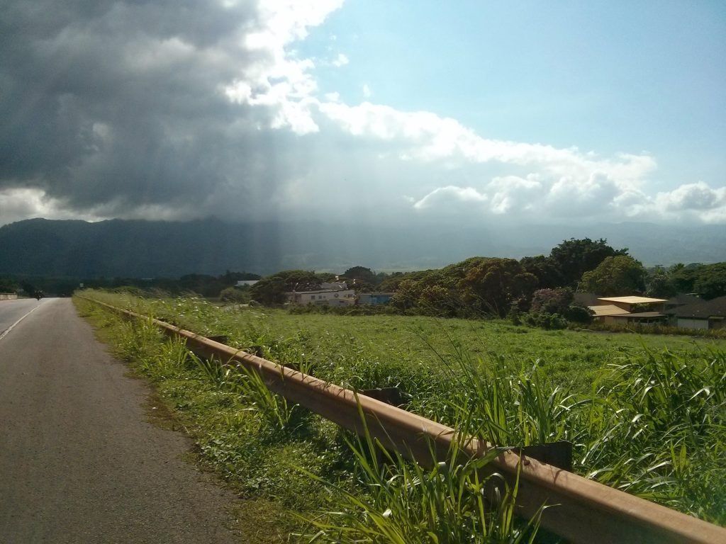A picturesque outdoor scene shows a lush green mountain landscape, featuring a large peak and a tranquil body of water. The harmonious setting suggests an idyllic location for relaxation and adventure, like hiking or enjoying nature.