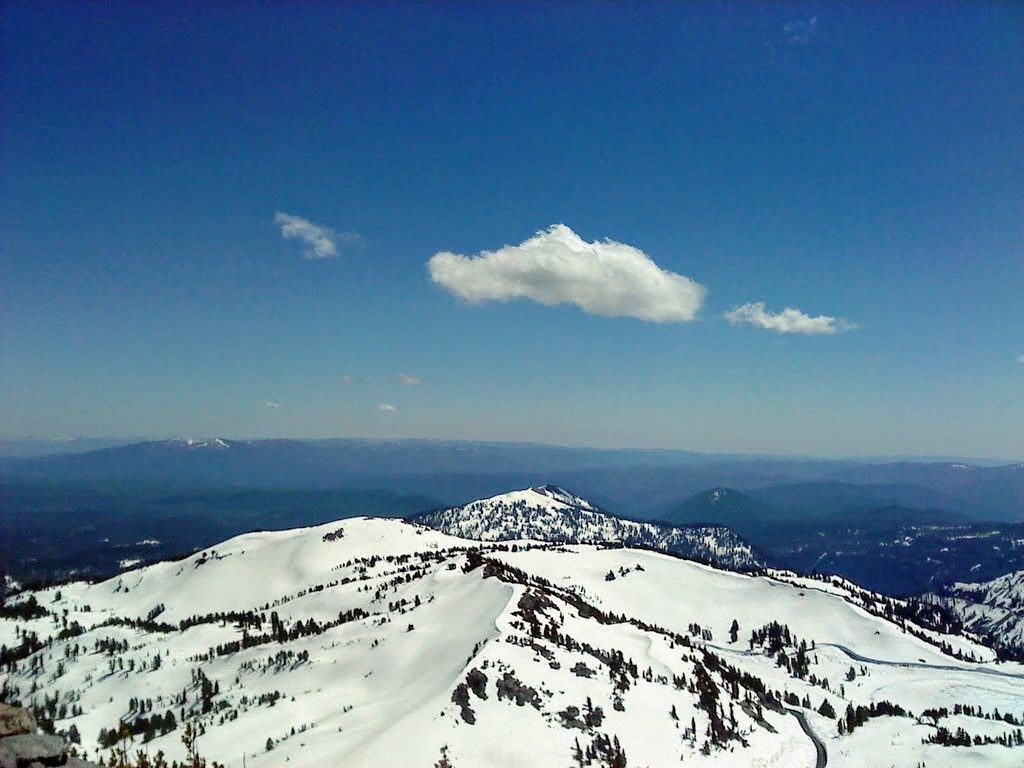 A scenic, snow-covered trail on Lassen Peak in California, viewed in landscape orientation. The trail is visually detailed with snow presence being highlighted.